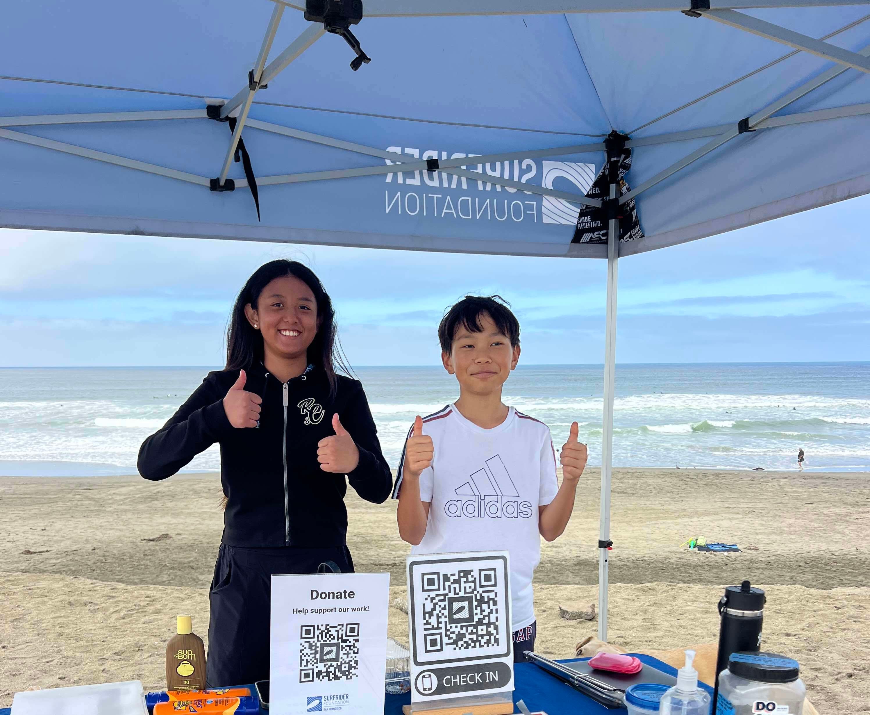 Two volunteers giving thumbs up at the Surfrider table