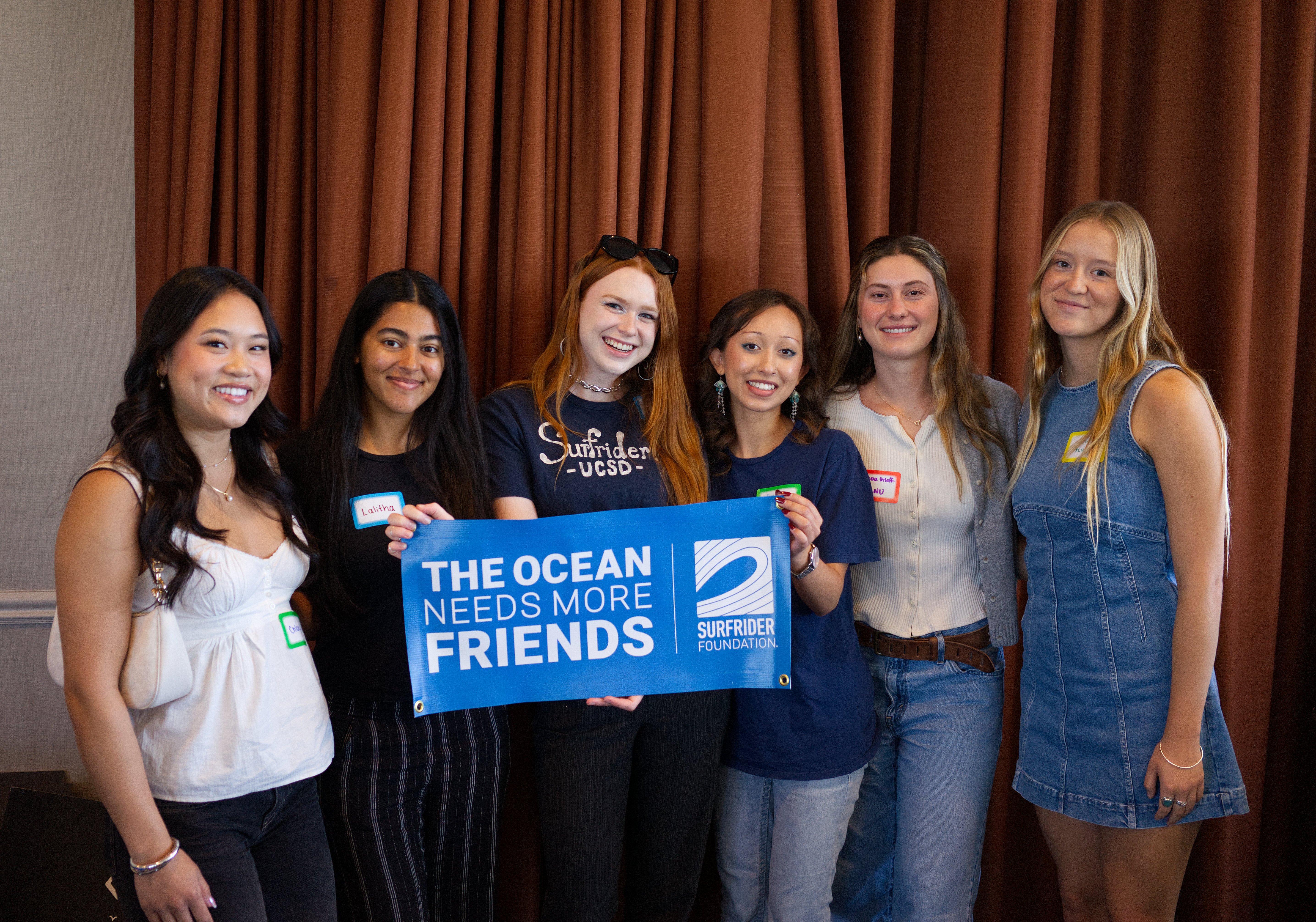 group posing with surfrider onmf sign